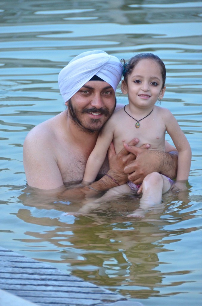 Padre sikh con su hija en el estanque de aguas curativas del templo